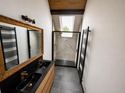 a bathroom with two sinks and a mirror at VinOli Holiday Home in Alveringem