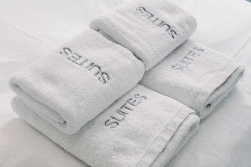three white towels sitting on a bed at InTown Suite in Lefkada