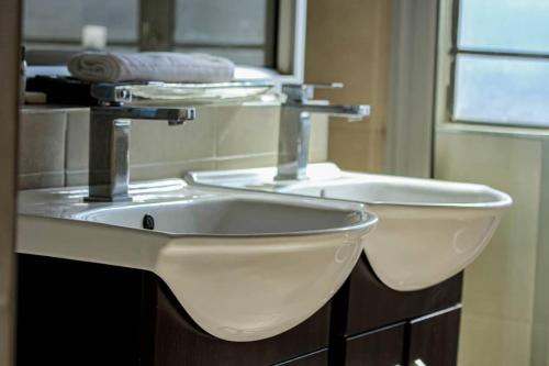 a bathroom with a white sink and a mirror at La Palma Suites Guest House in Mochudi
