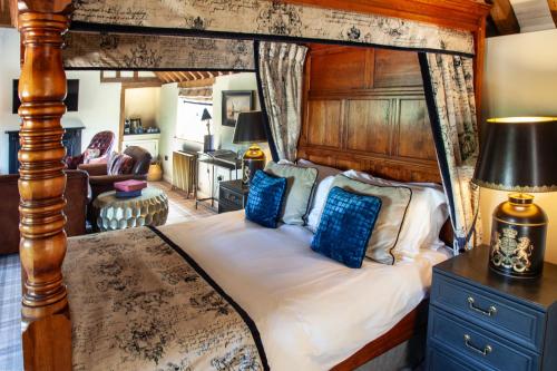 a bedroom with a large canopy bed with blue pillows at The Harcourt Arms in Witney