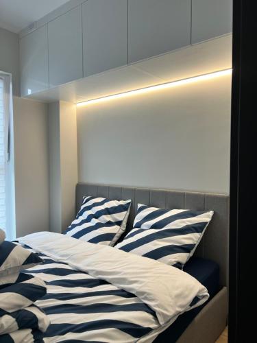 a bed with striped pillows on top of it at Apartament w Kębłowie in Kębłowo