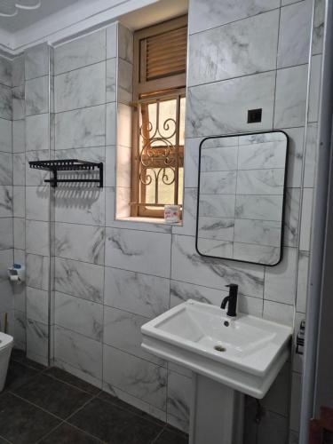 a bathroom with a sink and a mirror and a window at Pearl Stay in Entebbe