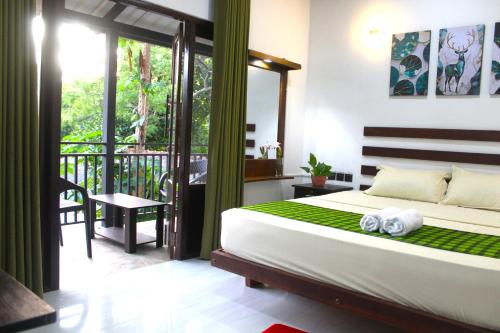 a bedroom with a bed and a balcony at The LeoEye Wilpattu in Pahala Maragahawewa