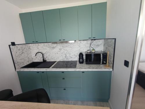 a kitchen with blue cabinets and a microwave at Vannes in Brest