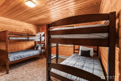 two bunk beds in a cabin with wooden walls at Lovely Log Cabin With Fire Pit! in Duck Creek Village