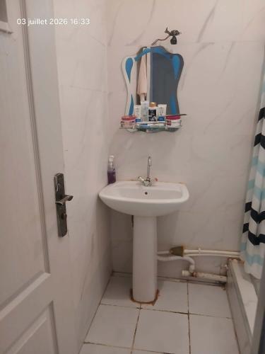 a white bathroom with a sink and a mirror at سكيكدة الجزائر in Skikda