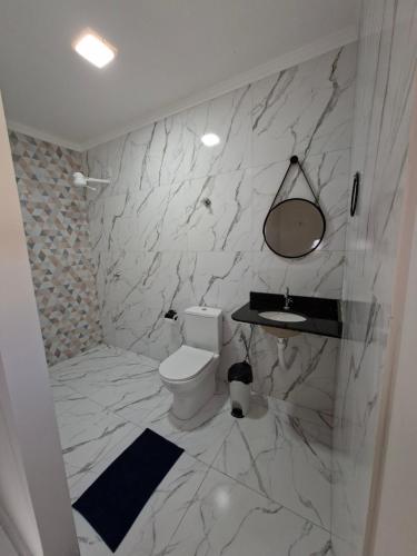 a white bathroom with a toilet and a sink at Conforto e Tranquilidade, Casa Completa in Martins