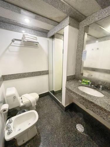 a bathroom with a toilet and a sink at Delphin Beach Hotel in Guarujá