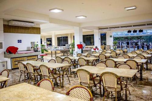 a dining room with tables and chairs in a restaurant at Lacqua DiRoma - Acesso livre ao Park Aquático - Central de Reservas in Caldas Novas