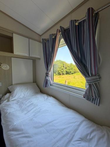 a small bedroom with a bed and a window at Beachcomber's Paradise in Castlegregory