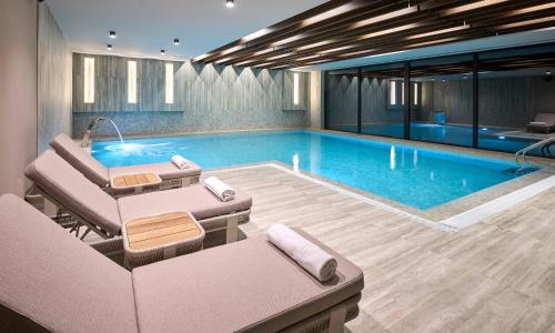 a large swimming pool with chairs and a couch at Aminess Florian & Godler Hotel in Karlovac