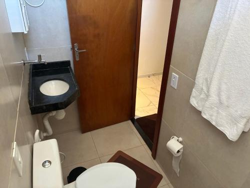a bathroom with a toilet and a wooden door at Pousada Apart Praia Uruaú in Beberibe
