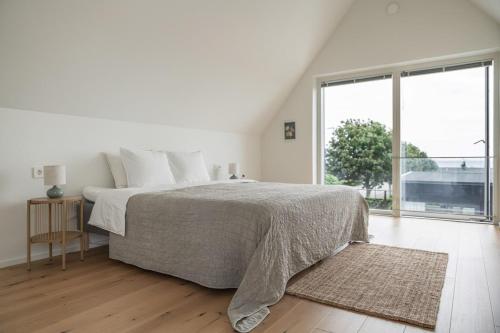 a white bedroom with a bed and a large window at Seaside villa with pool in Simrishamn