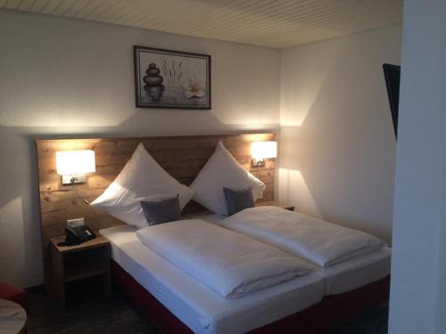 a hotel room with a bed with white sheets and pillows at Hotel Lamm in Waiblingen