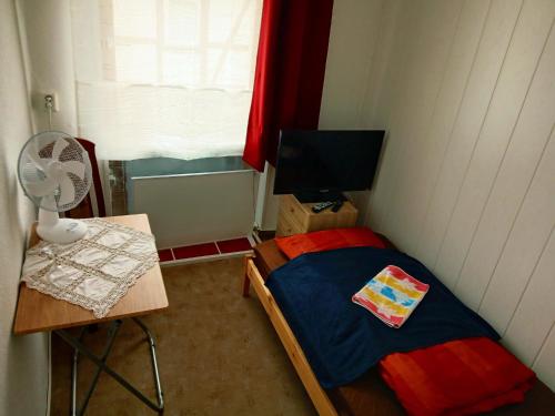a small bedroom with a bed and a table with a fan at Gasthaus & Pension Schmidt's in Haldensleben
