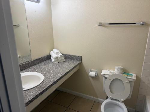 a bathroom with a toilet and a sink and a mirror at Sunshine Motel in Yakima