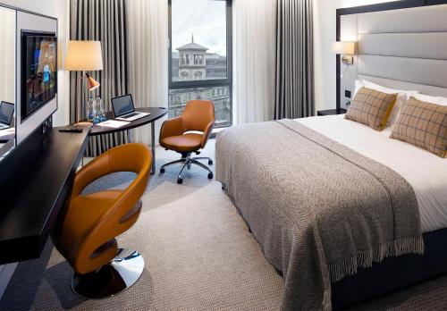 a hotel room with a bed and a desk with a computer at The Address Connolly in Dublin