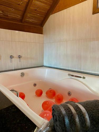 a bathroom with a tub with tomatoes in it at Chales Fazenda Cantinho do Selado in Monte Verde