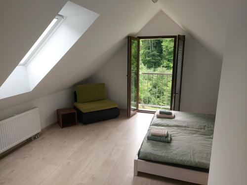 a attic bedroom with a bed and a window at Apartmán Lesný Dvor in Martinske Hole