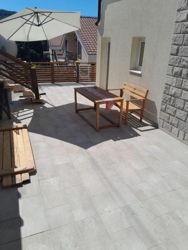 a patio with two benches and an umbrella at Apartman 4 sa spavacom in Zelenika