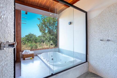 a bath tub in a bathroom with a large window at Pousada Vereda da Serra in Pirenópolis