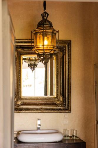 a bathroom with a mirror and a sink and a chandelier at Casa Lalla Hotel Rural in Douar Aguergour