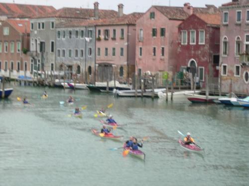 a group of people kayaking down a canal with buildings at Appartamento vacanzeCasadueottanta in Venice