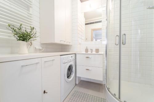 a white bathroom with a washing machine and a shower at Apartament Prowansalski in Nałęczów