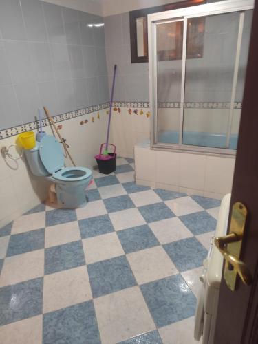 a bathroom with a blue toilet and a checkered floor at Aroui aireport in Nador Airport