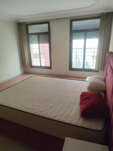 a large bed in a room with two windows at Aroui aireport in Nador Airport
