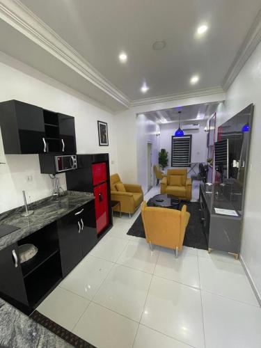 a kitchen and living room with yellow chairs in a room at JRC Chariot Luxury Apartment in Omole