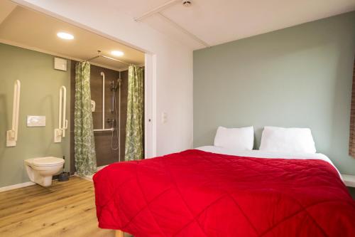 a bedroom with a red bed and a toilet at Premiere Classe Liege / Luik in Liège