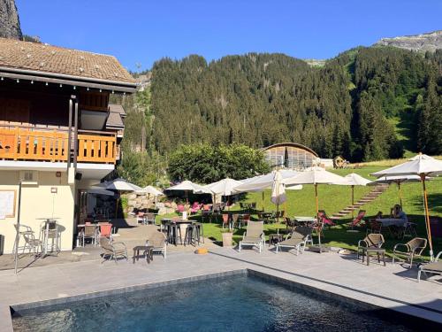 a resort with a swimming pool and tables and umbrellas at Hameau des Prodains - Hôtel in Morzine