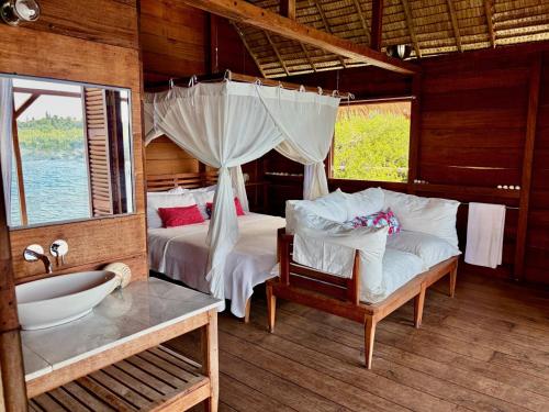 a bedroom with two beds and a tub and a sink at ipyum Premium Overwater Guest House in Pulau Birie