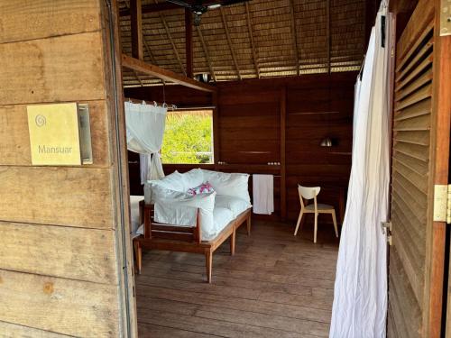 a room with a bed and a chair in a building at ipyum Premium Overwater Guest House in Pulau Birie