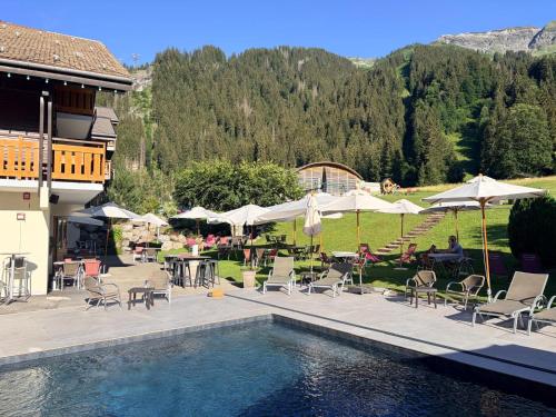 a swimming pool with chairs and tables and umbrellas at Hameau des Prodains - Résidence in Morzine