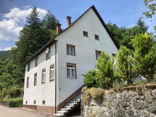 a large white house with a stone wall at Obergießhof Waldbauernhof in Hornberg