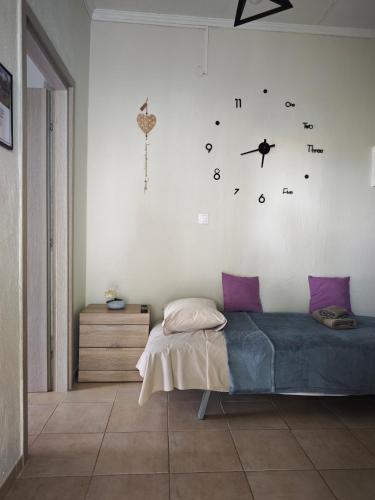 a bedroom with a bed and a clock on the wall at Elina House and Garden in Nikiti