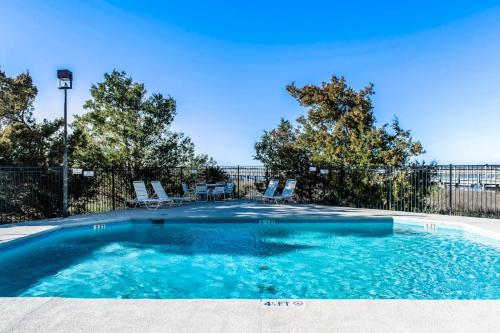 a swimming pool with blue water and chairs at Bay Creek Villa - 311 in Edisto Beach