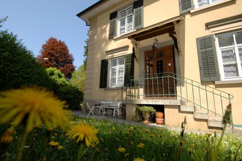 a house with a porch and a lawn with flowers at The Bed + Breakfast in Luzern
