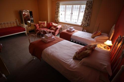 a hotel room with three beds and a chair at The Old Bear Inn in Cricklade