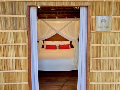 a bed with two red pillows in a room at ipyum Premium Beach Guest House in Sageurin