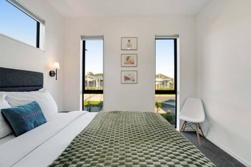 a white bedroom with a large bed and a chair at Cosy Pukekohe Self-Contained Unit with Kitchenette in Pukekohe East
