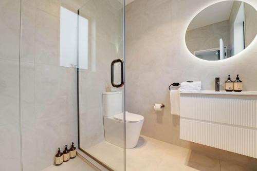 a bathroom with a shower with a toilet and a mirror at Cosy Pukekohe Self-Contained Unit with Kitchenette in Pukekohe East