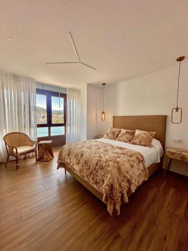 a bedroom with a large bed and a chair at GH Beiramar in Cee