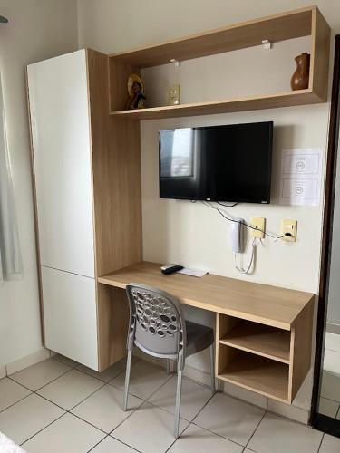 a desk with a television and a chair in a room at Hotel Piracema Caruaru in Caruaru