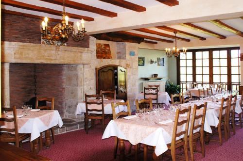 une salle à manger avec des tables, des chaises et une cheminée dans l'établissement Le Fenelon, à Carennac