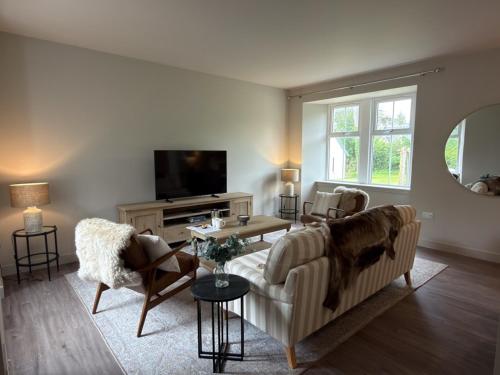 a living room with a couch and chairs and a tv at Greenkeepers Cottage in Tobermory