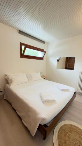 a bedroom with a large white bed with a window at Riflesso Apartment in Blevio