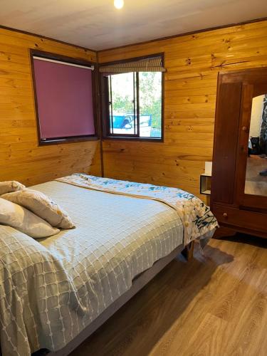 a bedroom with a bed in a room with wooden walls at Refugio Lawentu Linares Colbun in Los Rabones